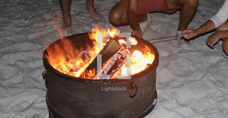 roasting marshmallows over a fire on the beach 