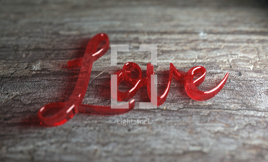 The word Love is spelled out in glass on a wooden background