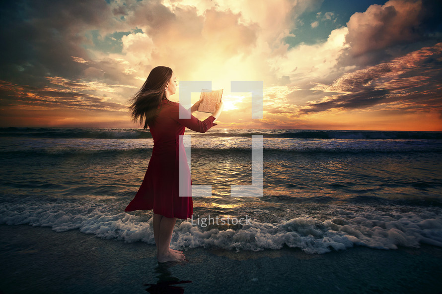 woman reading a Bible on a beach at sunrise 