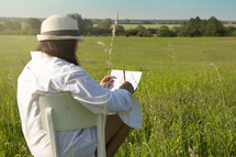 a woman sketching a drawing in a field 