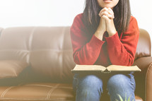 a woman praying with a Bible on her lap 