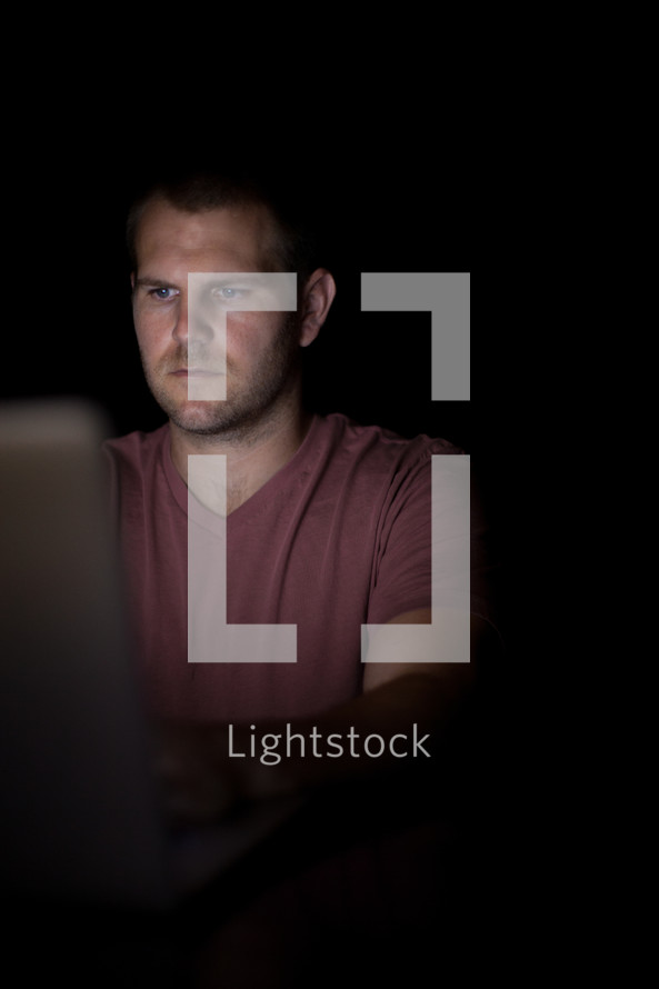 A young man illuminated by light from a computer.