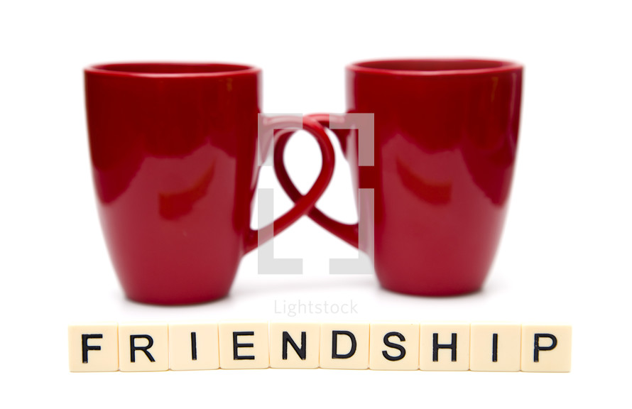 red coffee mugs and word friendship in scrabble pieces 