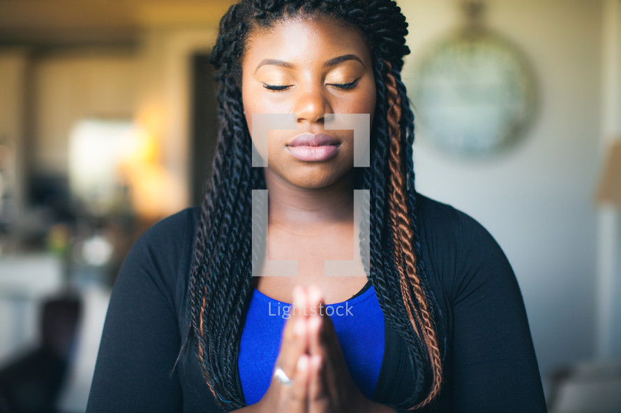 African American woman with closed eyes and praying hands 