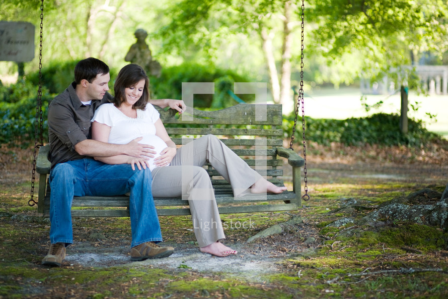 expecting couple sitting on a park bench
