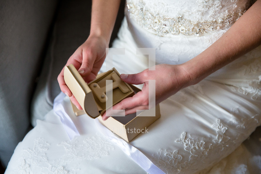 A bride opening a small box containing diamond earrings.