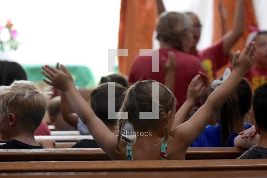 enthusiastic children with raised hands singing worship songs at VBS