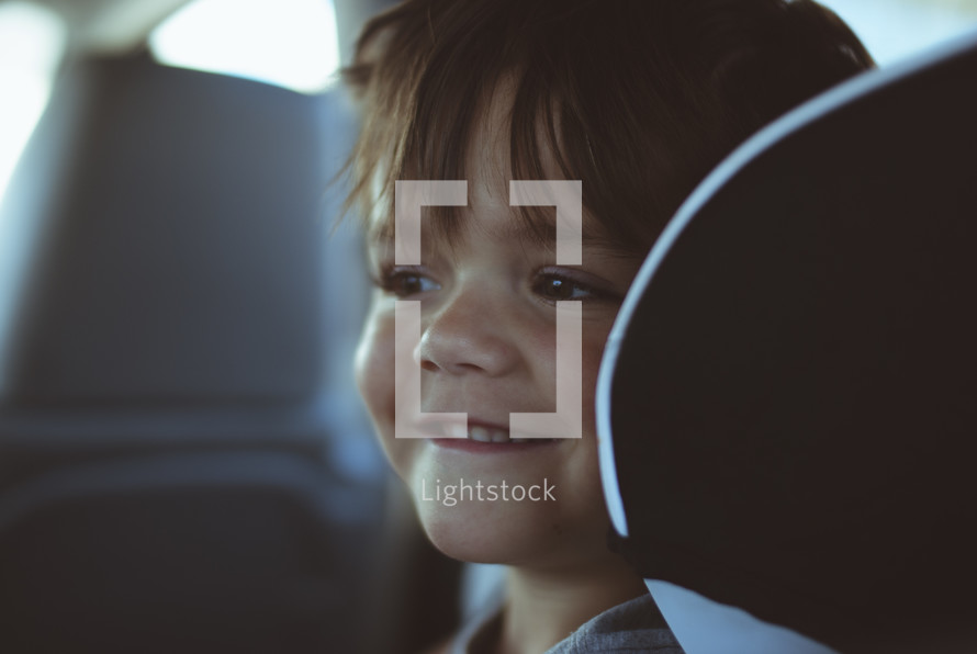 smiling child in the backseat of a car 