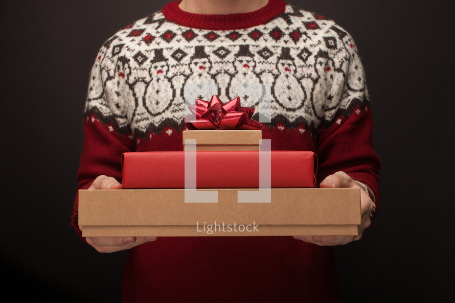 a man holding a stack of Christmas gifts 