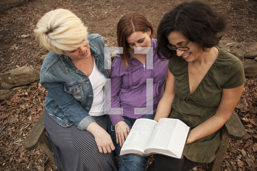 three woman reading a Bible together 