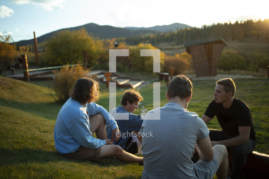 young men sitting outdoors talking 
