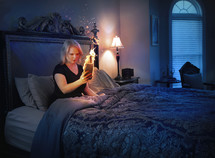 A woman looks at her cell phone on fire in her bedroom