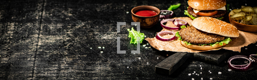 A burger on a stone board on a table. On a black background. High quality photo