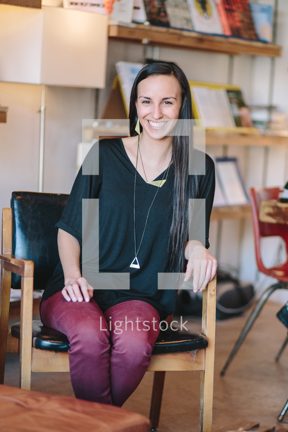 a smiling woman sitting in a chair 