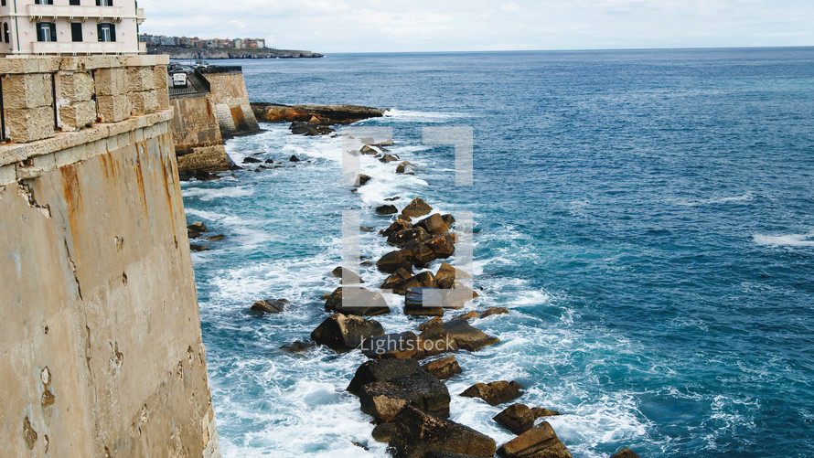 Waves of ocean crashing in rocks in Syracusa city in Sicily