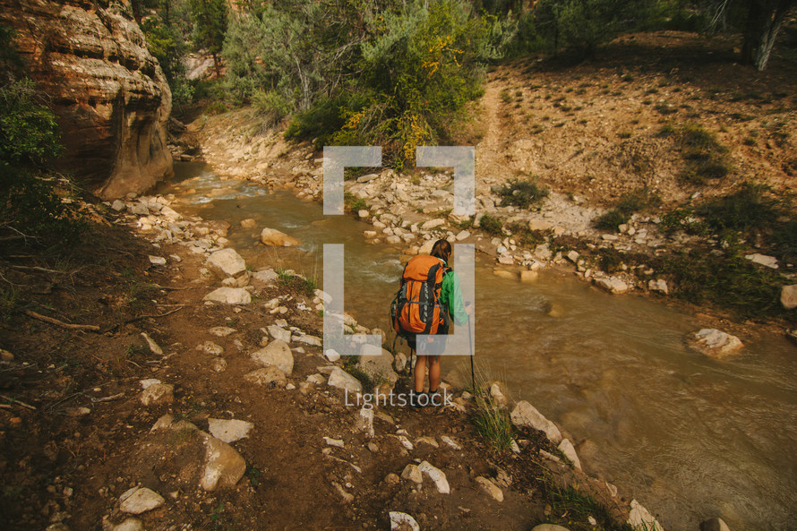 a woman backpacking along a stream 