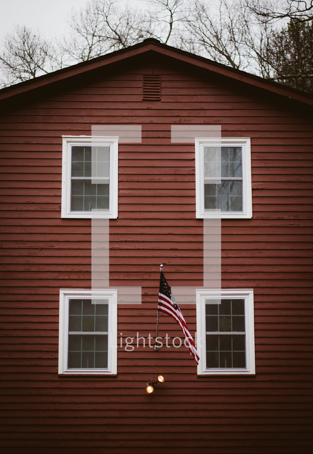 American flag on the side of a red house 
