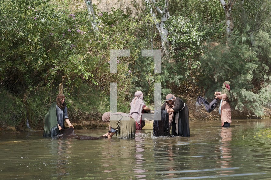 women washing clothes in a river during biblical times 