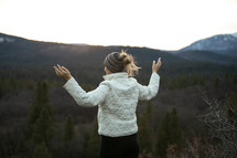woman on a mountain with raised hands 