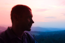 side profile of a man with mountains in the background 