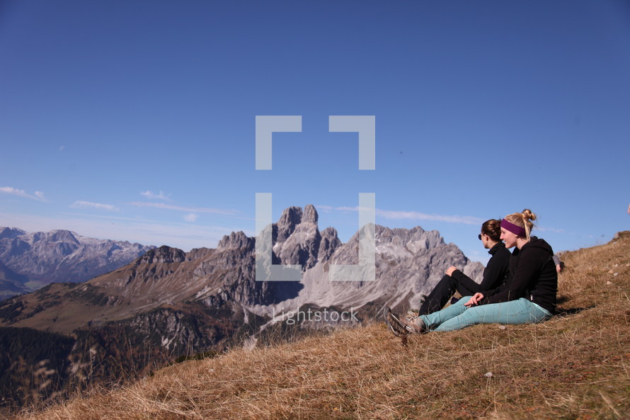 women sitting on a mountainside 