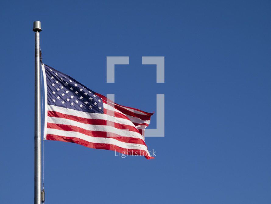 An American flag flying against a blue sky.