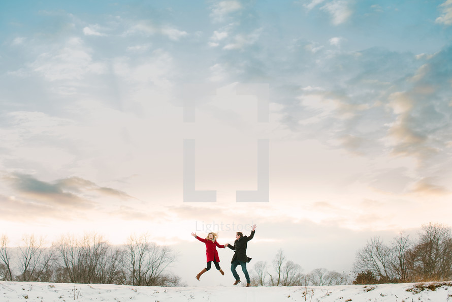 a couple jumping outdoors in snow 