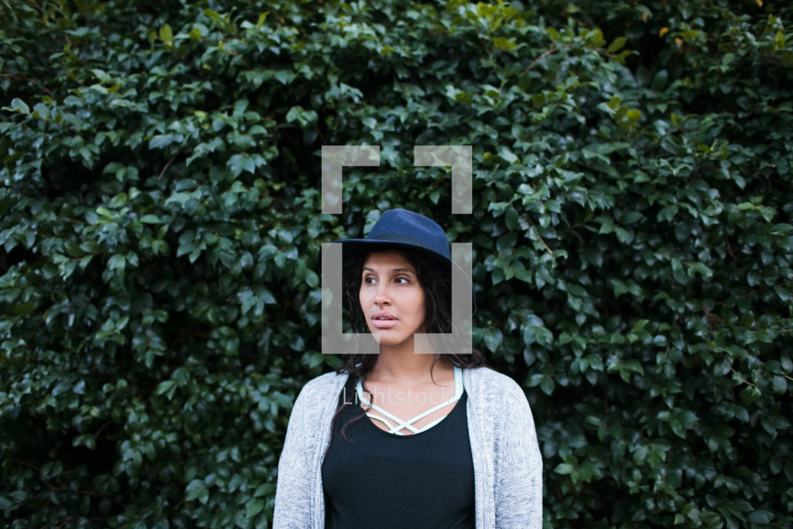 head shot of a woman in a hat in front of ivy