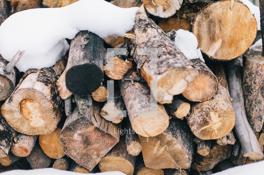 snow on a stack of firewood 
