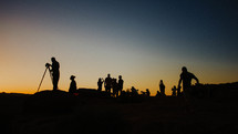silhouettes of people on a mountaintop at sunset 