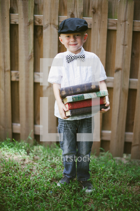 boy child holding a stack of school books 
