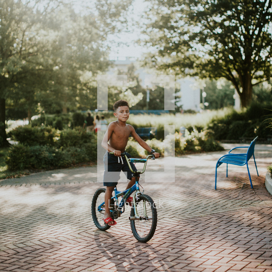 young shirtless boy riding a bicycle 