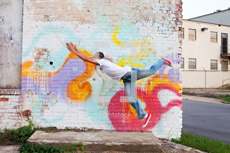 a man leaping in front of street art