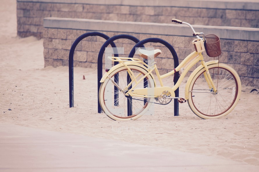 yellow beach cruiser bike on a bike rack 