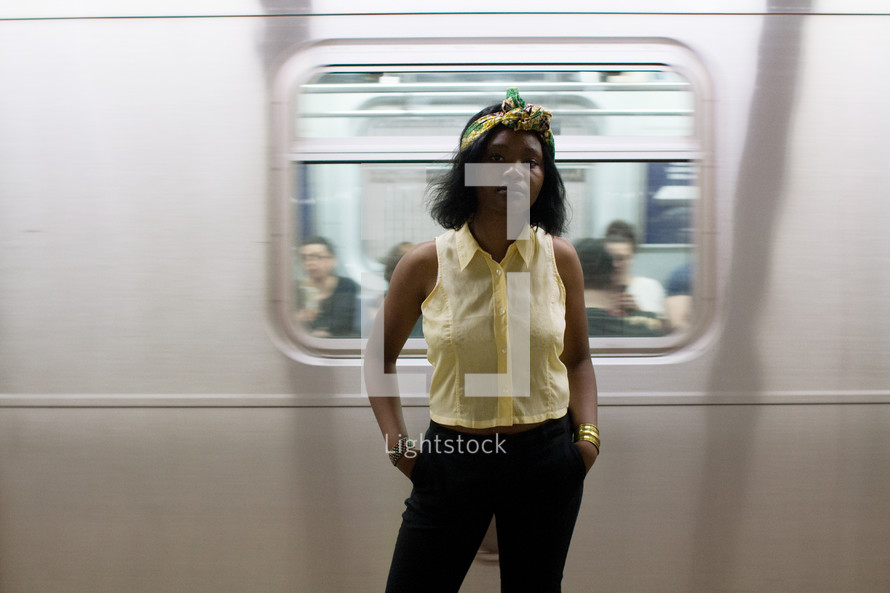 a woman standing in front of a passing subway train 