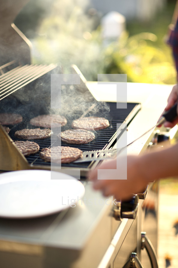 a man cooking hamburgers on the grill 