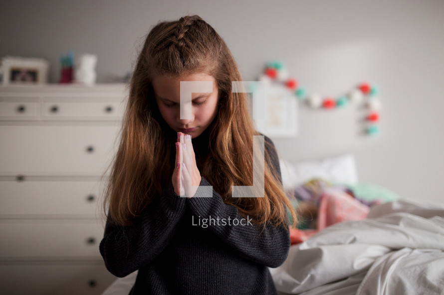 a girl praying bedside 