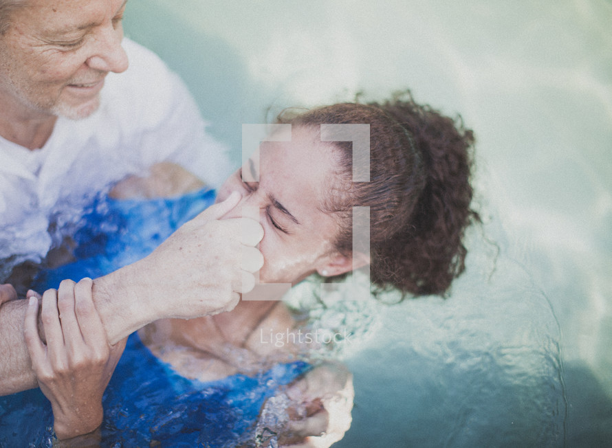 Man baptizing a girl in a pool of water.