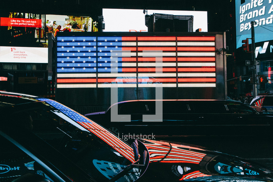 American flag on a marquee sign and passing cars 