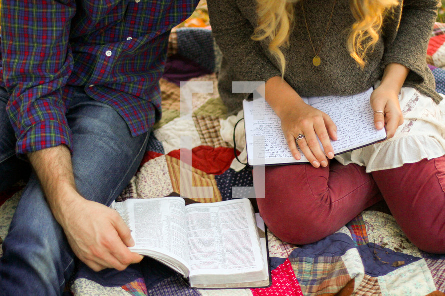 couple sitting on a blanket reading a Bible 