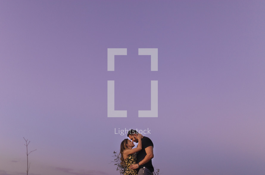 a couple kissing under a purple sky 