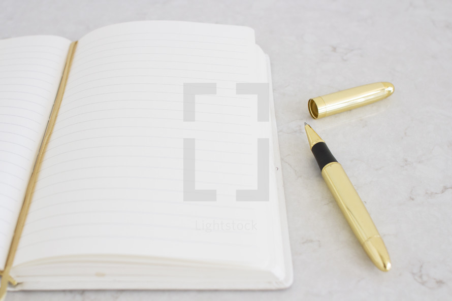 A blank notebook and a gold pen.