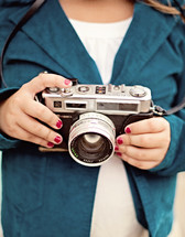woman with painted nails holding a camera 