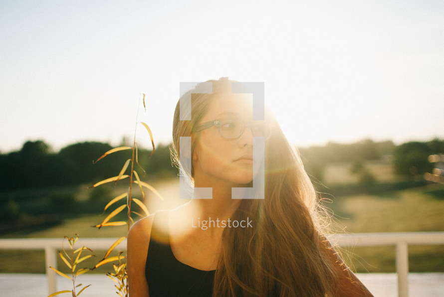 portrait of a young woman standing under sunlight 
