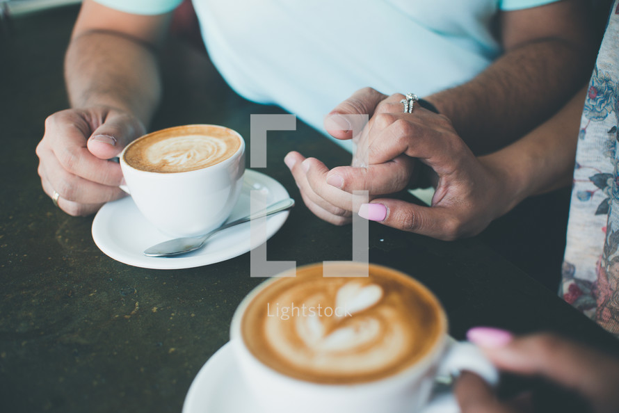 a couple holding hands and drinking coffee 