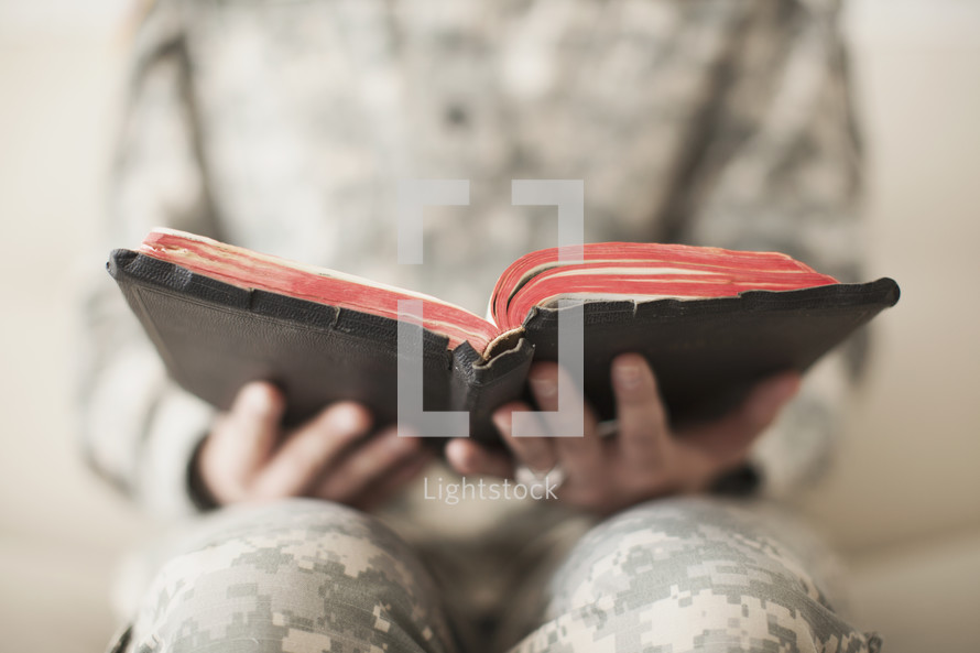 Female soldier holding an open Bible.