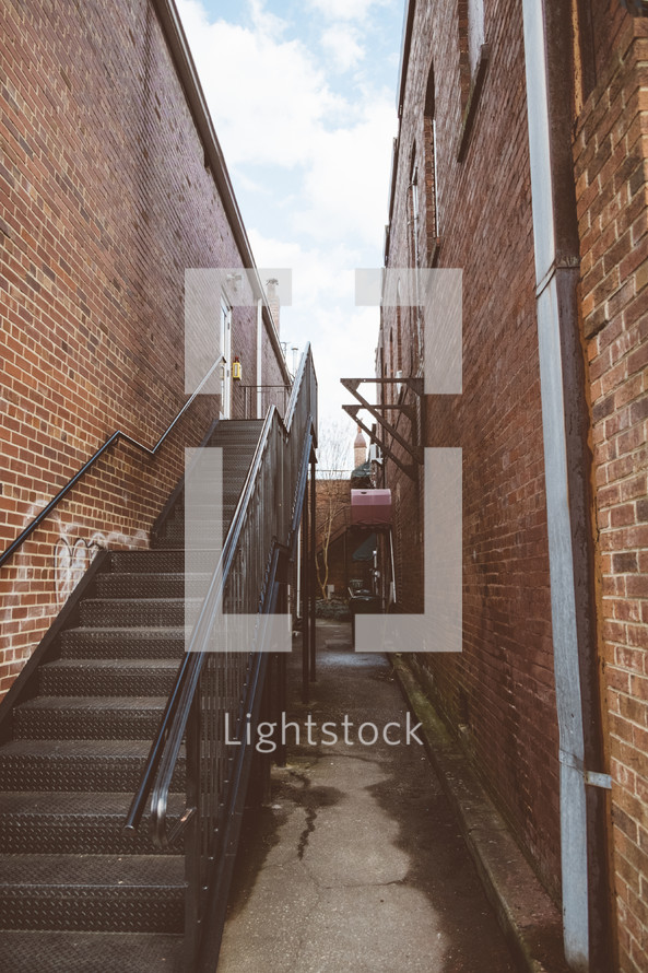 Stairway in an alley between two brick buildings.