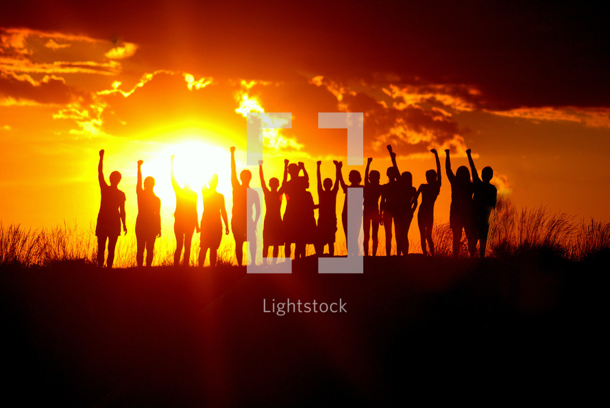 Young people silhouetted holding up their arms