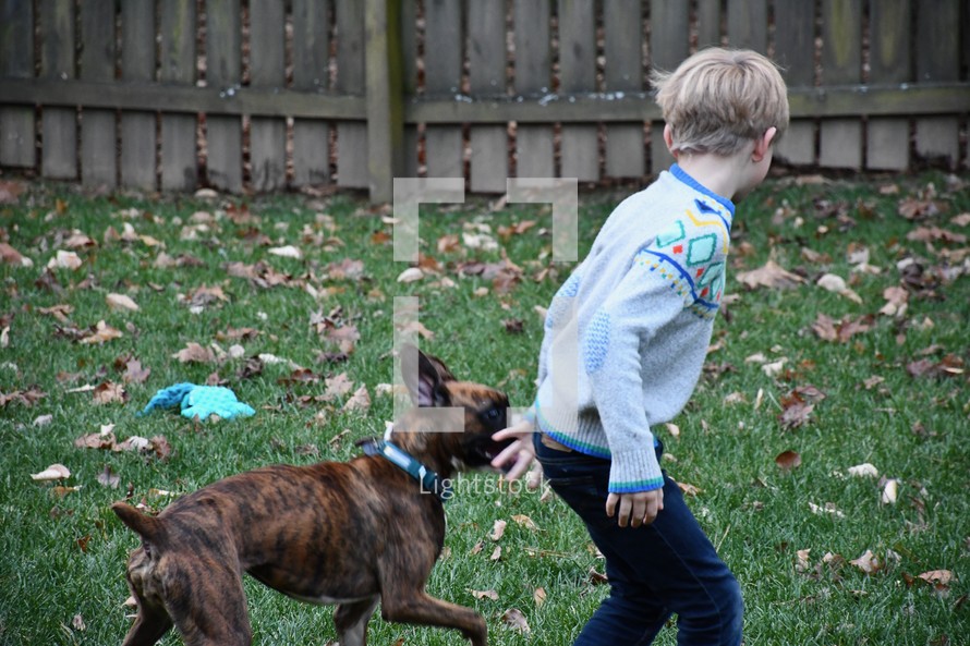 a boy playing with his dog in the backyard 