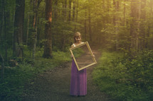 woman holding a mirror in a forest 
